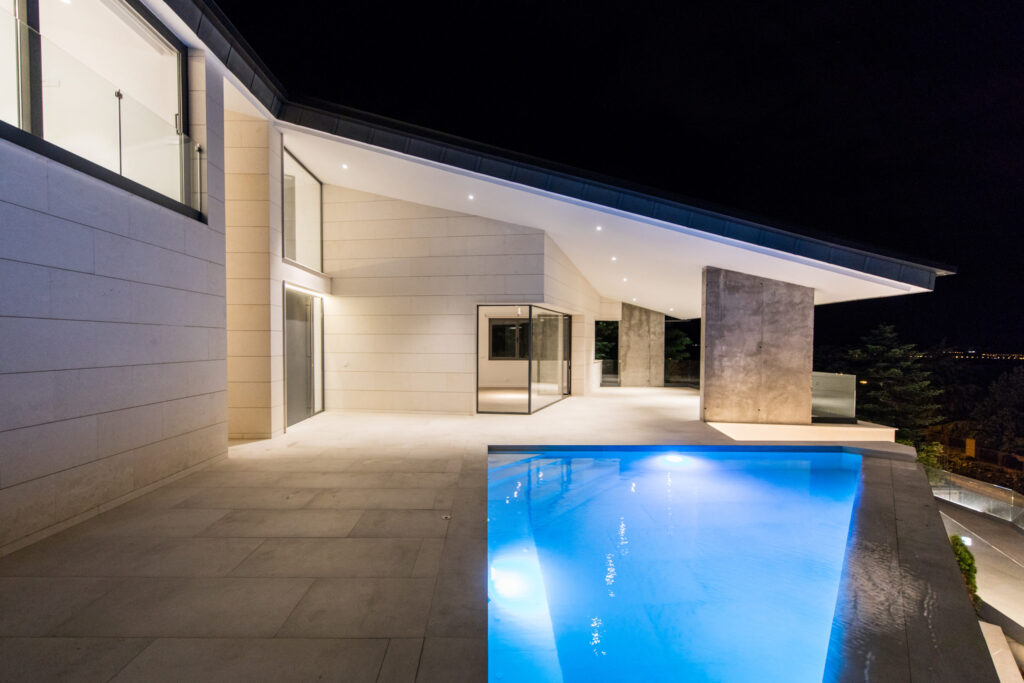 Vivienda de diseño contemporáneo con piscina exterior iluminada y terraza nocturna