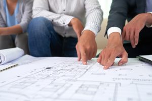 Clientes y asesor inmobiliario revisando planos durante una reunión de venta de vivienda