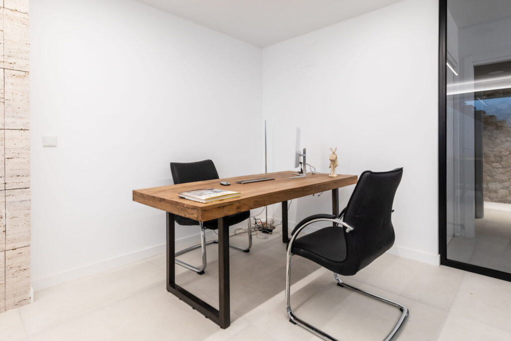 Oficinas de Spacio4 con despacho moderno, mesa de madera, sillas negras y diseño minimalista en espacio de trabajo profesional