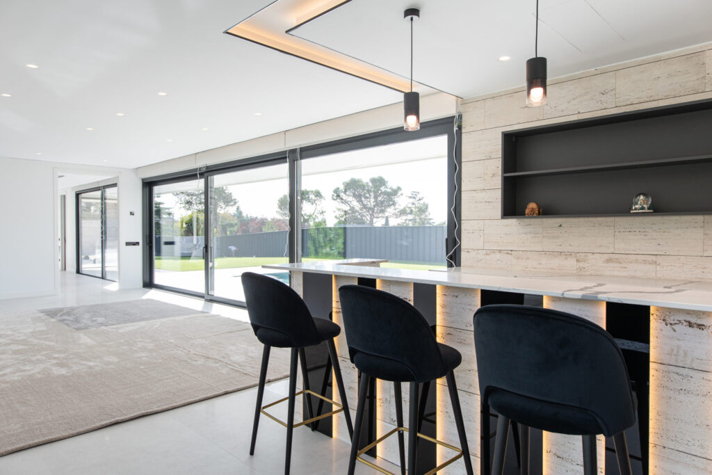 Cocina moderna abierta con isla, taburetes y grandes ventanales ideal para fotos inmobiliarias y venta de vivienda