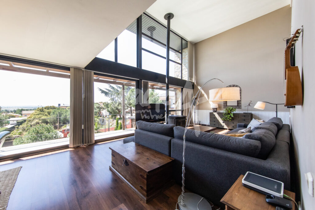 Salón moderno con ventanales grandes de doble altura que aportan luz natural y amplitud