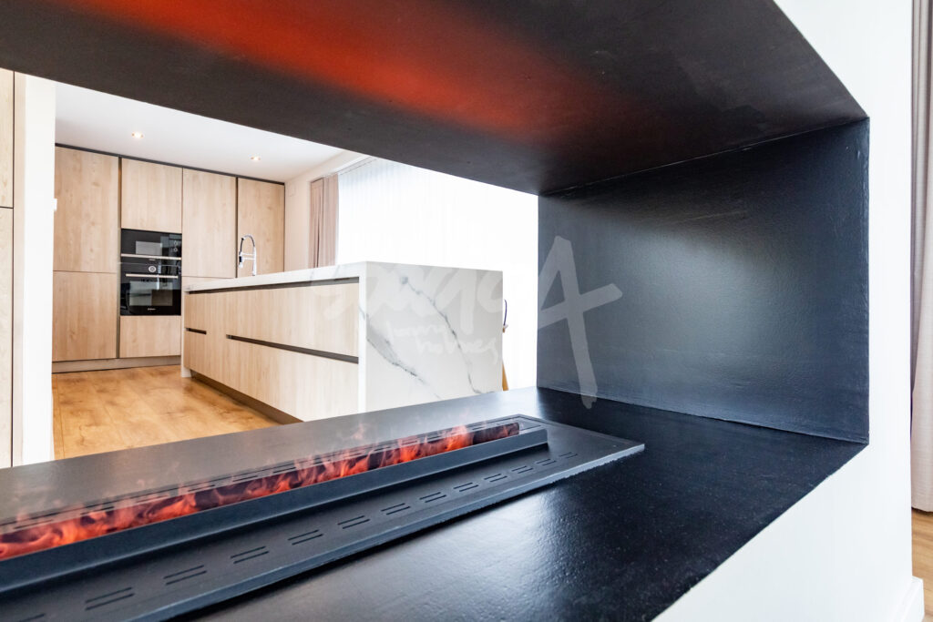 Cocina moderna con isla central y chimenea integrada en vivienda de lujo en Boadilla del Monte