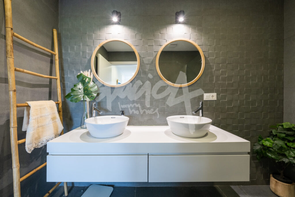 Baño moderno con lavabos dobles, espejos redondos y elementos de madera natural