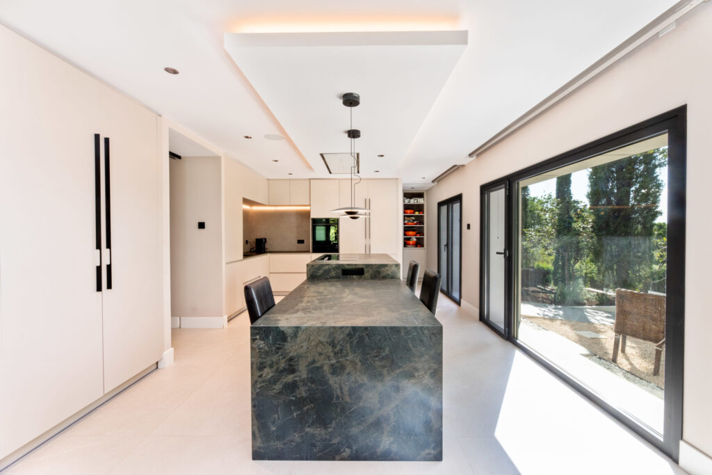 Cocina moderna con isla central, mobiliario minimalista y grandes ventanales al jardín