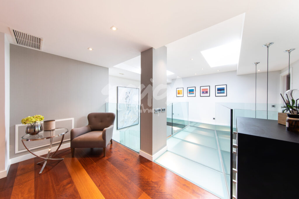 Buhardilla reformada y decorada como espacio habitable con suelo de madera, luz natural cenital y diseño moderno
