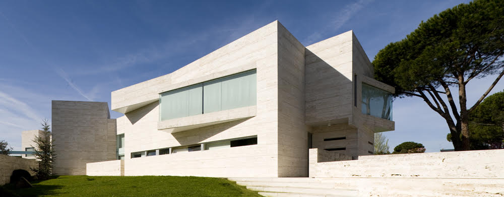 Vivienda unifamiliar de arquitectura contemporánea con volúmenes geométricos, fachada de hormigón visto y grandes ventanales
