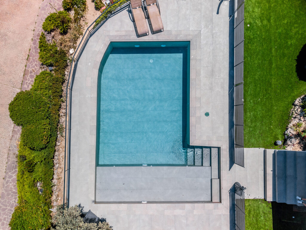 Piscina privada de vivienda unifamiliar en calle Cabo Peñas vista aérea con solárium y zonas ajardinadas