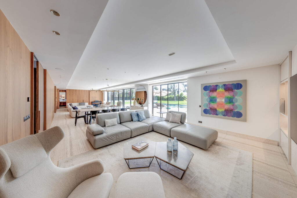 Salón amplio y luminoso con sofá modular, grandes ventanales y diseño interior contemporáneo