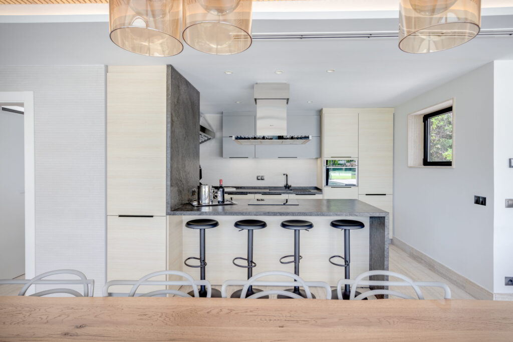 Cocina moderna con isla central, barra con taburetes y mobiliario de líneas minimalistas