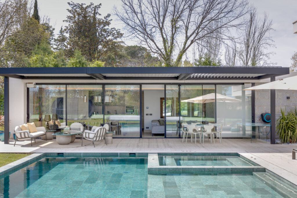Vivienda contemporánea con grandes ventanales, porche cubierto y piscina privada exterior
