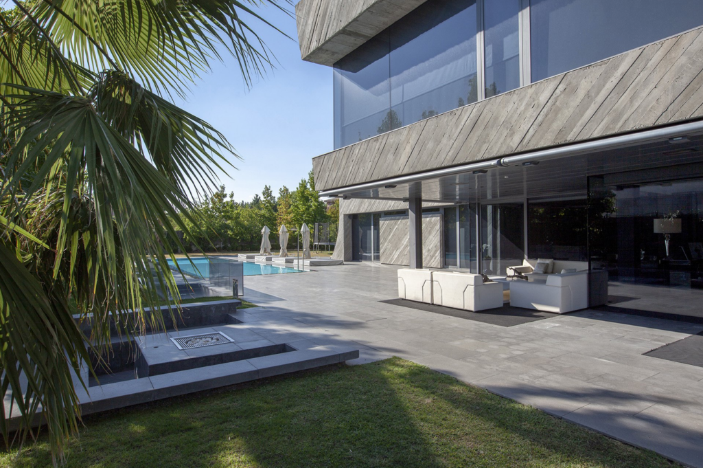 Exterior de vivienda de diseño con piscina, terraza pavimentada y fachada de hormigón visto
