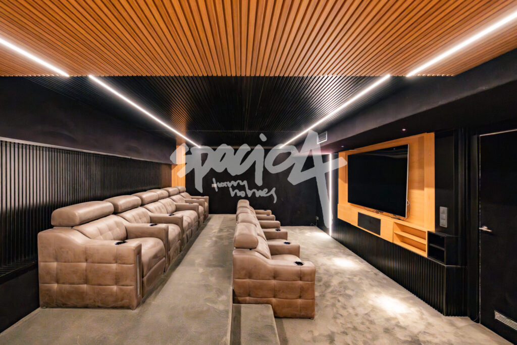 Sala de cine privada en vivienda de lujo con butacas reclinables, iluminación integrada y techo de madera